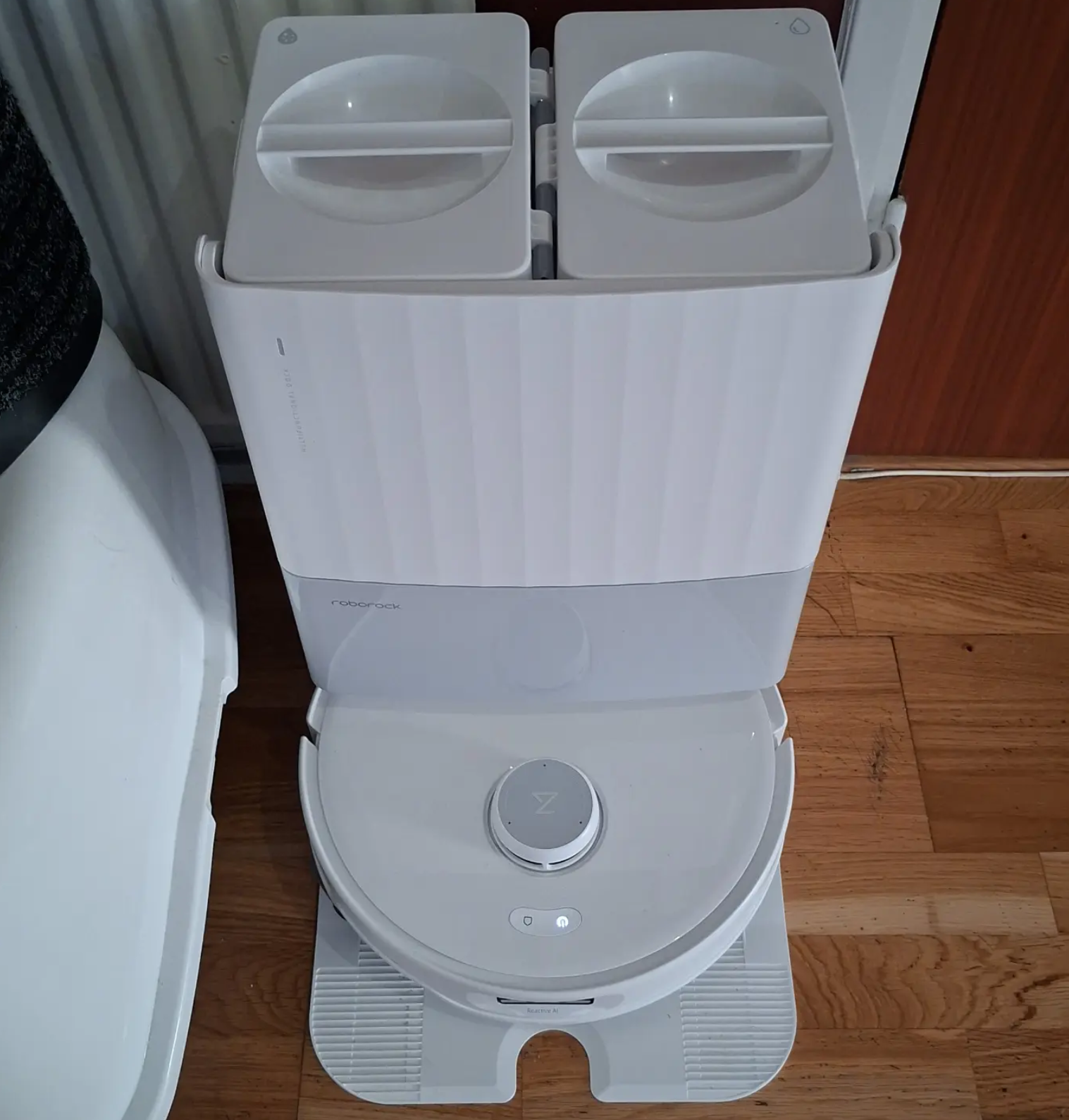 White Roborock robot vacuum at its docking station on a wooden floor