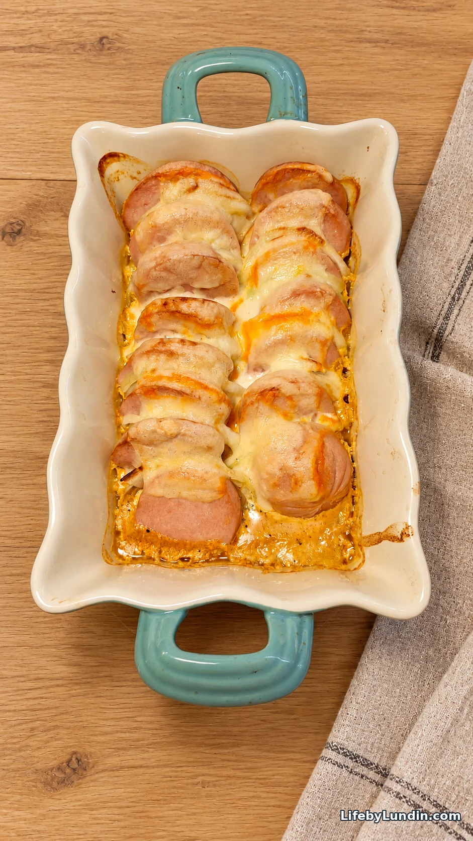 Curry falukorv bake with cheese in a white baking dish with turquoise handles